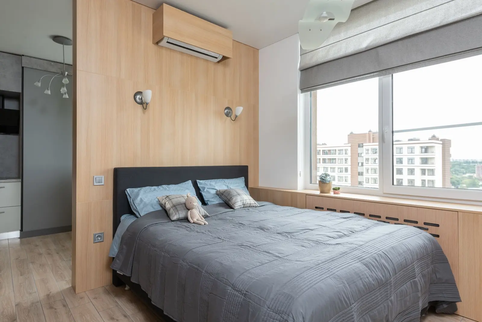Condo bedroom with a grey bed, wood panelling and a wide window