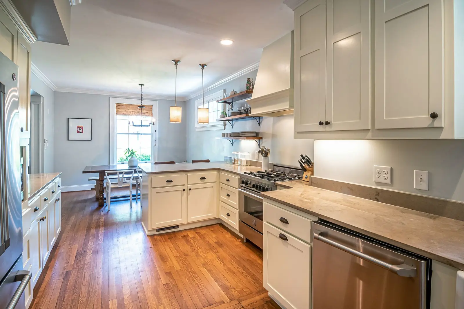 Cream-cabinet kitchen with wood floors, a gas range and an eat-in dining table
