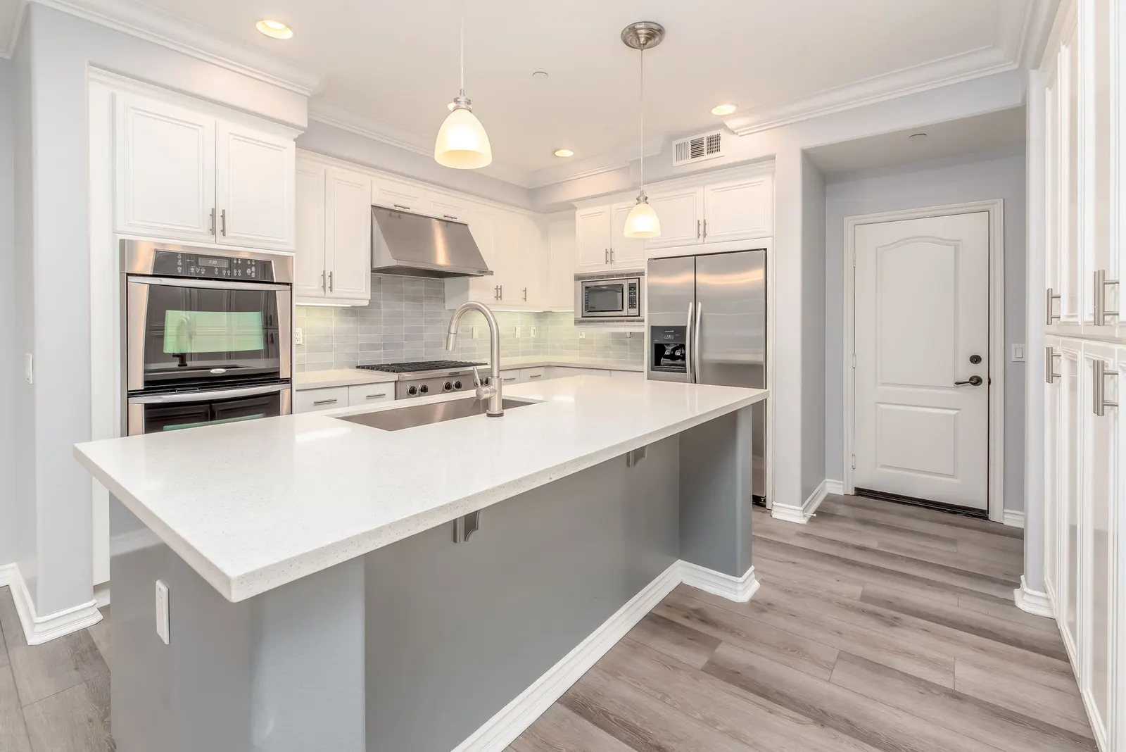 White kitchen with a quartz island and stainless appliances