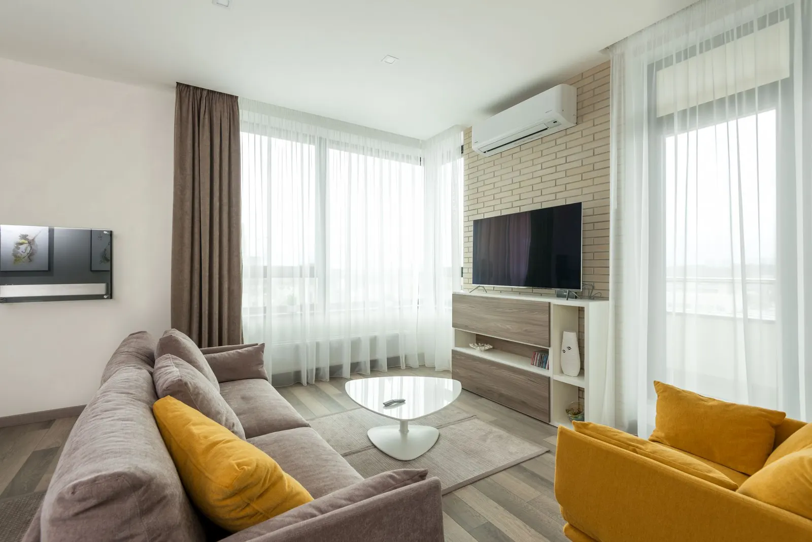 Bright living room with a grey sofa, yellow armchair and sheer curtains