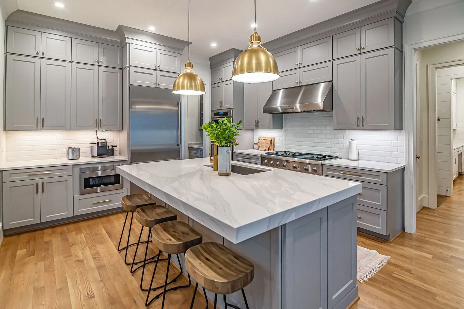 Grey shaker kitchen with a marble-look island, brass pendants and an oak floor